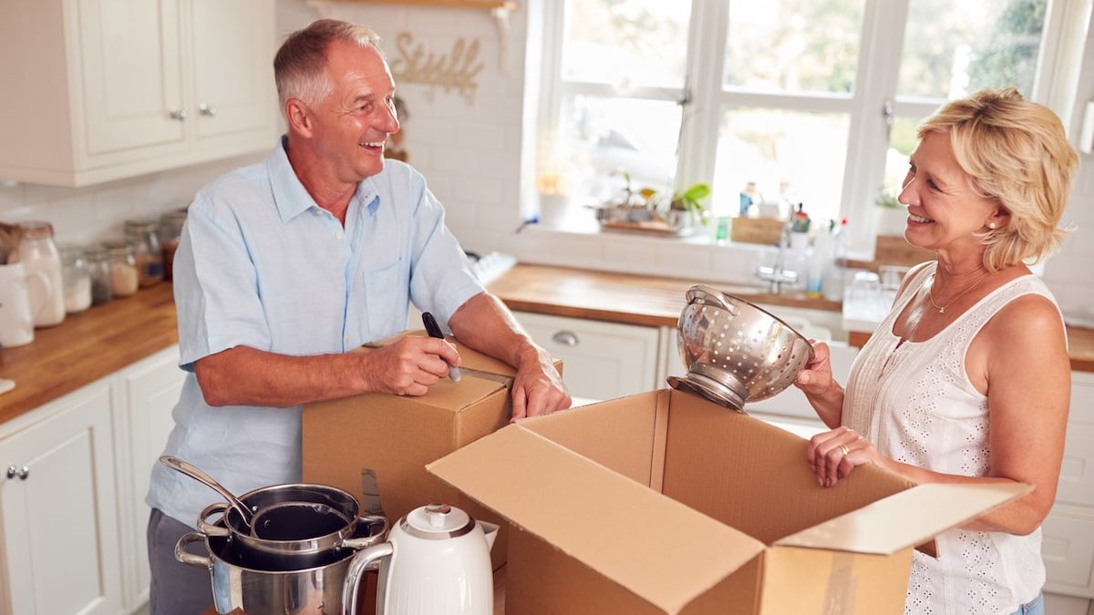 happy couple packing kitchen supplies into boxes